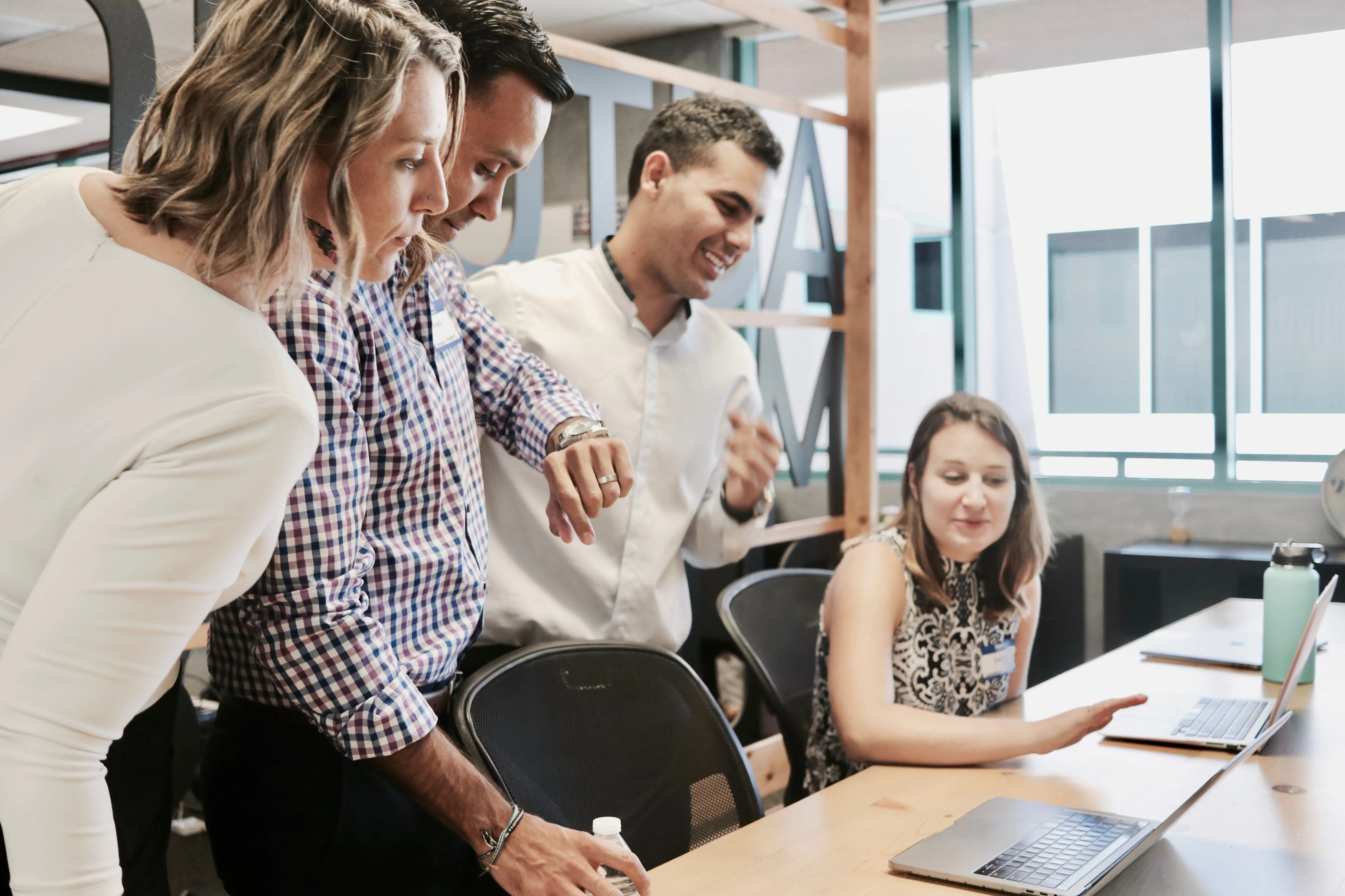 A group of people standing around a table with laptops.